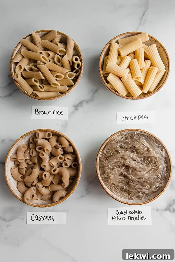 Bowls filled with various types of gluten-free pasta, showcasing different shapes and textures, alongside fresh ingredients like tomatoes and herbs.