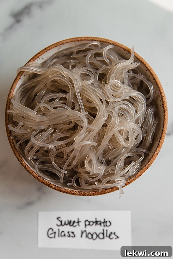 A bowl of cooked Korean sweet potato glass noodles, highlighting their translucent appearance and long, slender form.