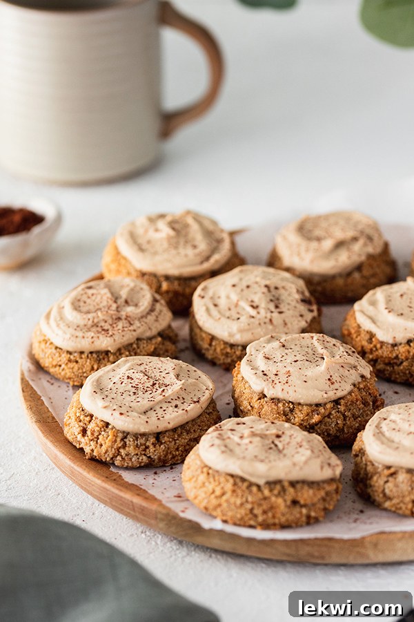 Delicious tiramisu cookies on a white plate, each topped with creamy frosting and dusted with cocoa powder.