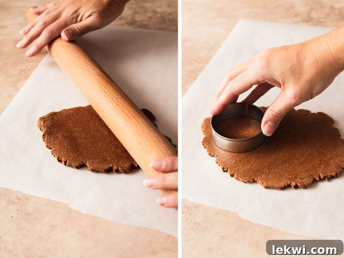 Rolling out gingerbread cookie dough on parchment paper with a rolling pin.