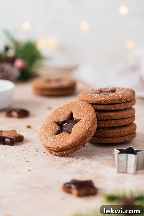 A stack of six chocolate gingerbread sandwich cookies, showing the layers and the star cutout.
