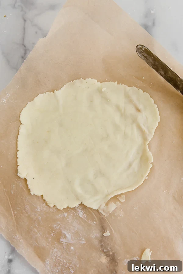 A thin, round sheet of sweet potato lefse dough, perfectly rolled out on parchment paper.