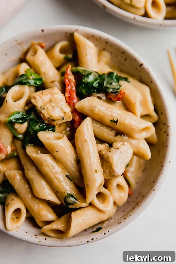 A beautiful bowl of creamy Tuscan chicken pasta, garnished with fresh parsley.