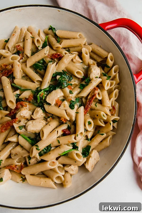 A Dutch oven filled with creamy Tuscan chicken pasta, steaming and ready to be served.