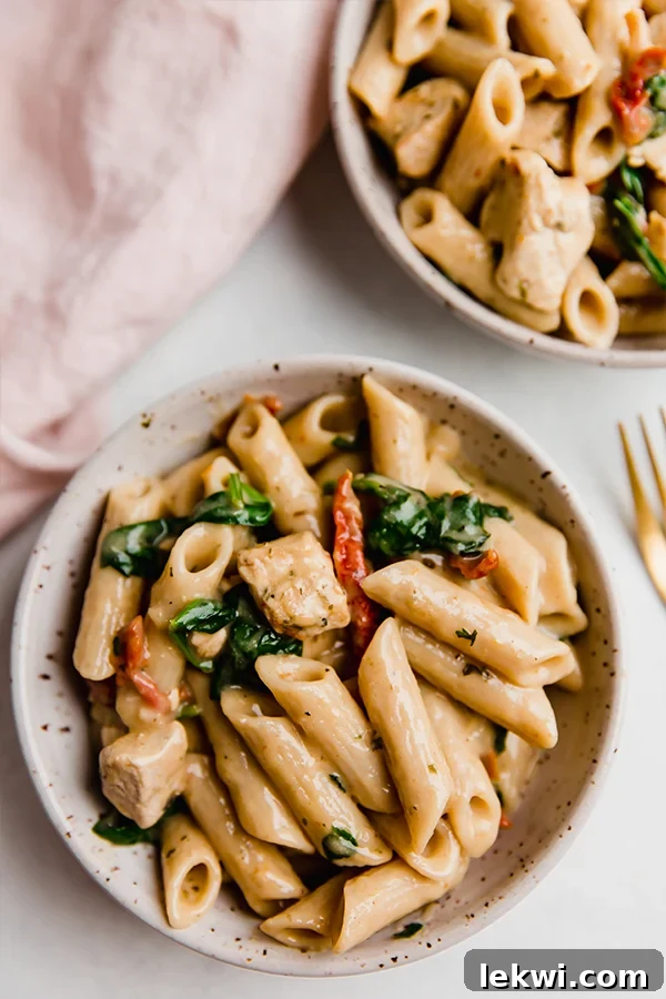 Creamy Tuscan chicken pasta in a serving dish, beautifully arranged and garnished with fresh herbs.