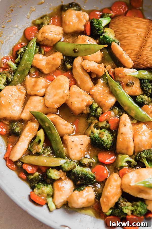 Orange chicken stir fry in a pan.