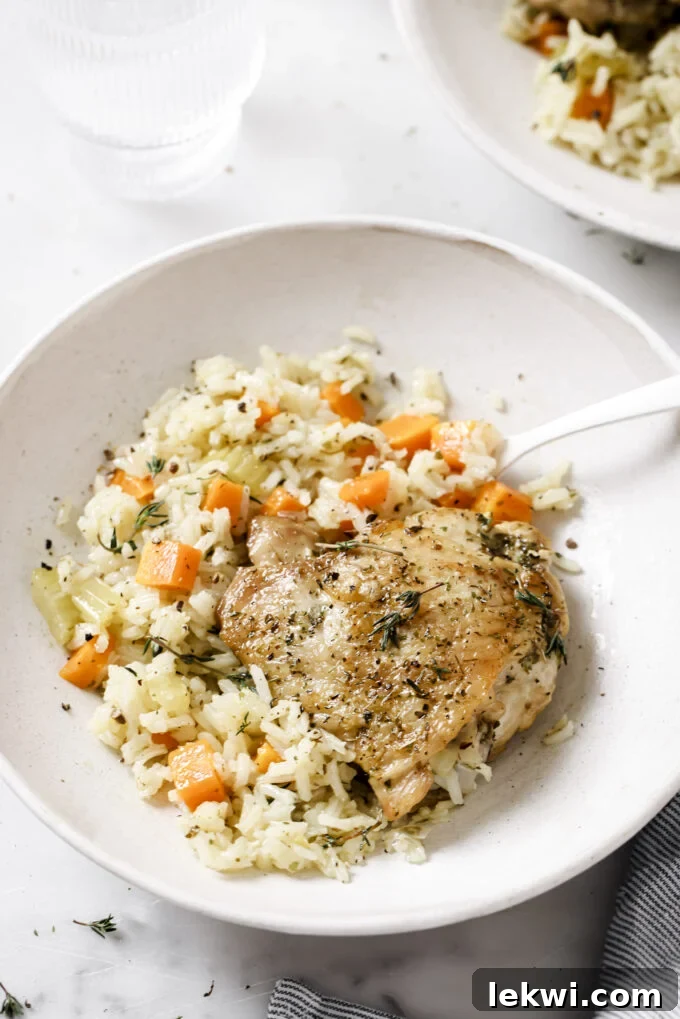 One pot baked chicken and rice in a white bowl topped with herbs.