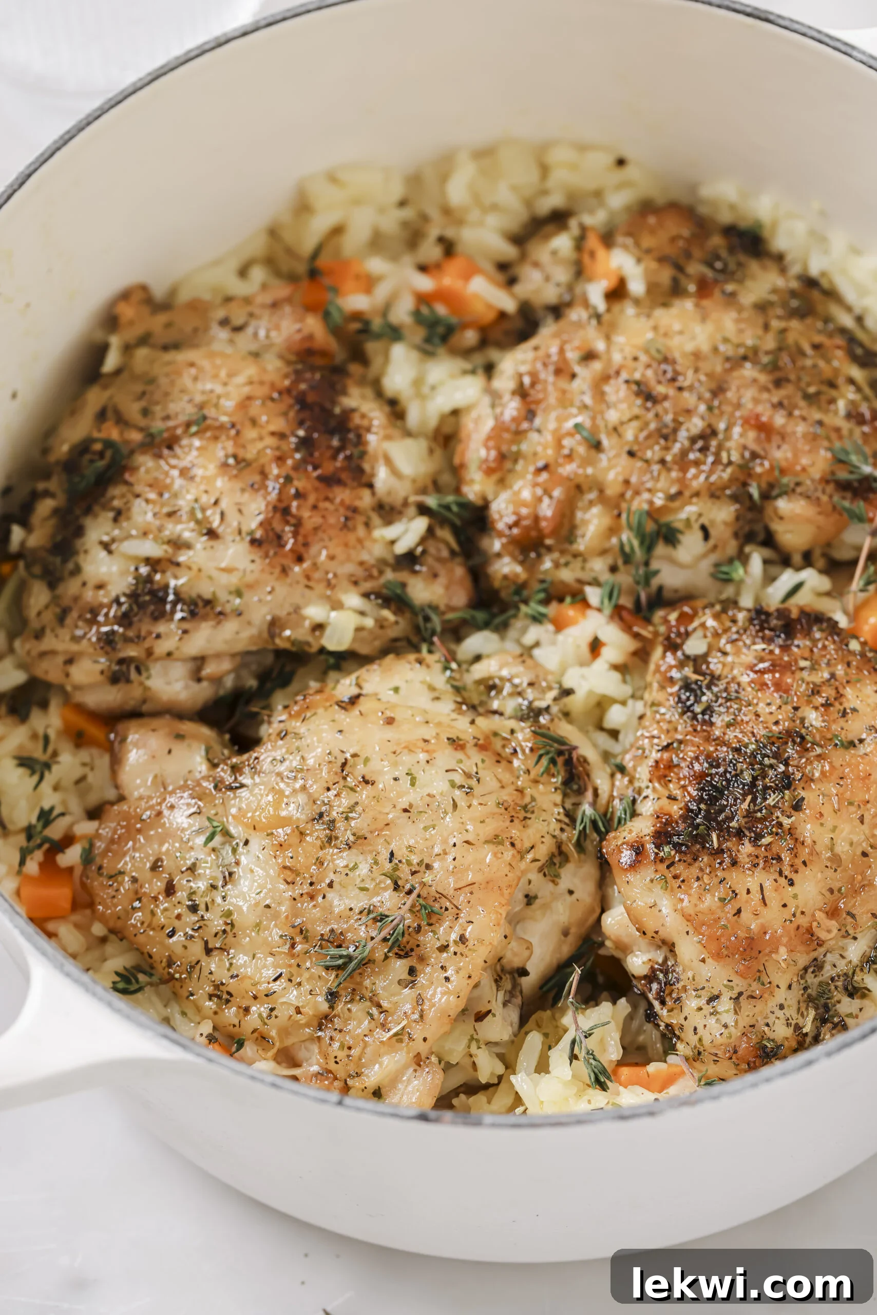 One pot baked chicken and rice in a large white pot topped off with fresh herbs.