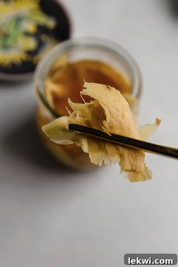 Chopsticks lifting pickled ginger out of a jar.