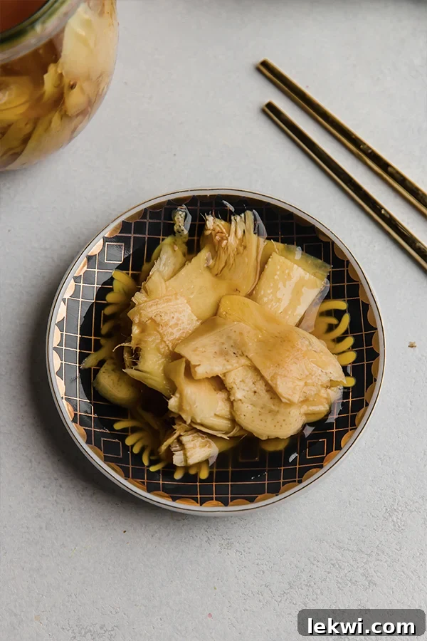 Chopsticks next to pickled ginger in a small bowl.