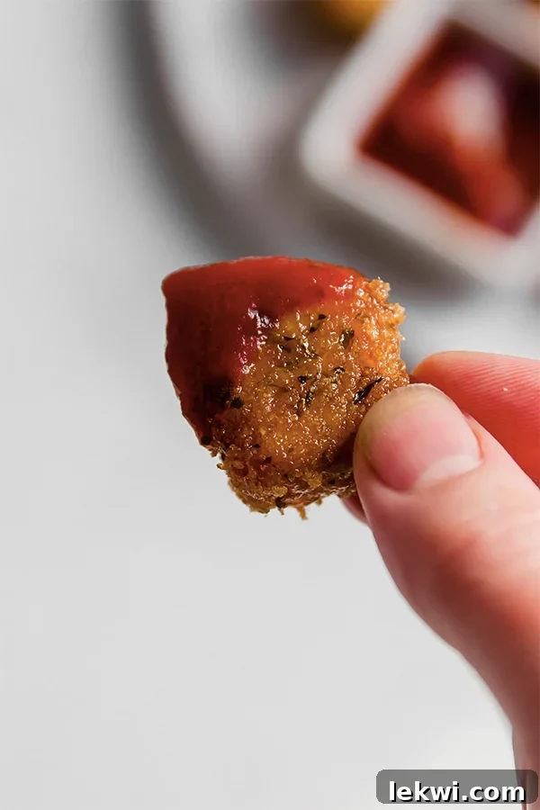 A single crispy pork panko chicken nugget shown with a blob of dipping sauce next to it.