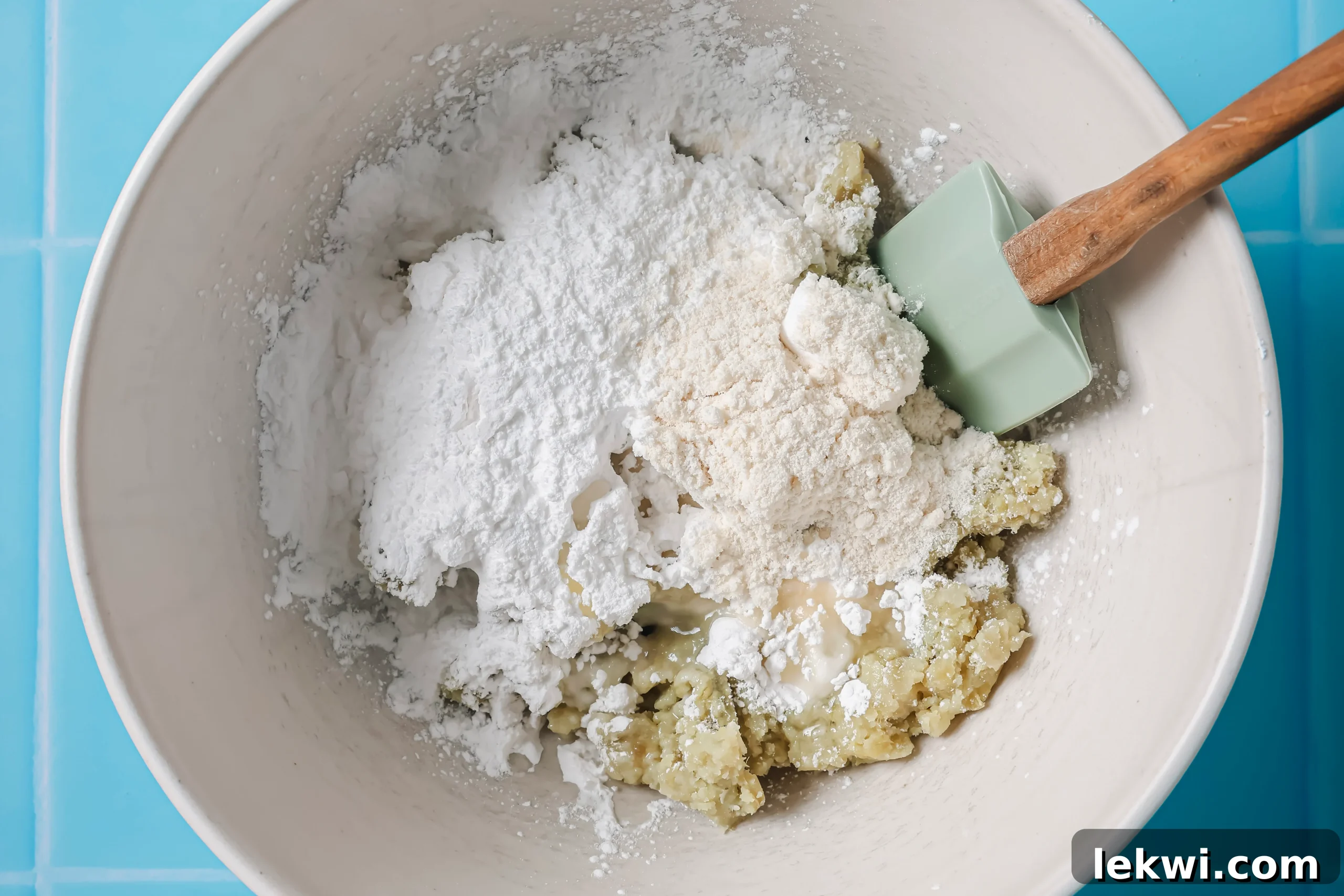 Unmixed ingredients for sweet potato smiley fries in a bowl, showcasing the mashed sweet potato, arrowroot starch, coconut flour, avocado oil, and salt before combining.