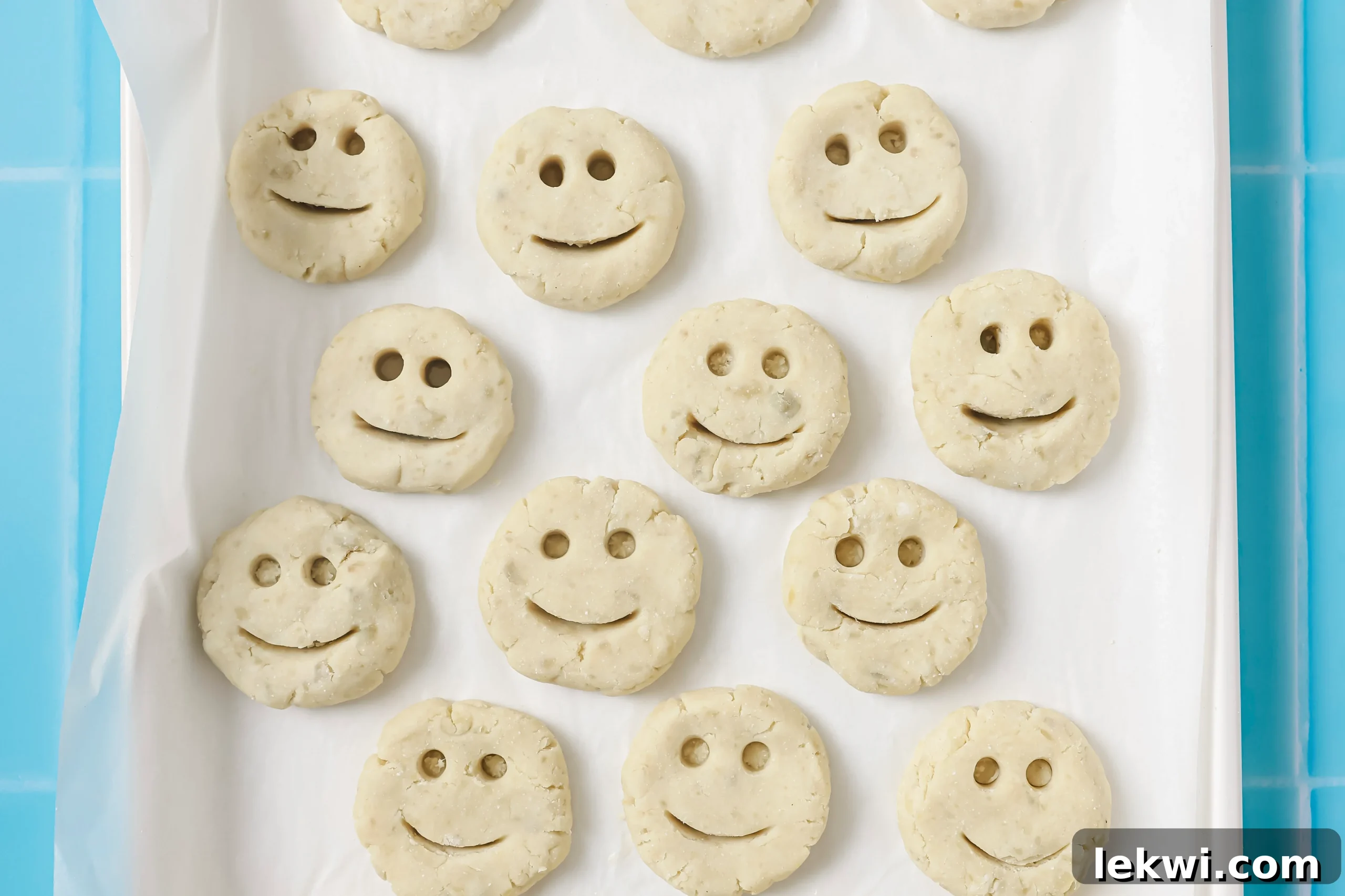 Uncooked sweet potato smiley fries neatly arranged on a baking sheet, displaying their cute facial features before baking.