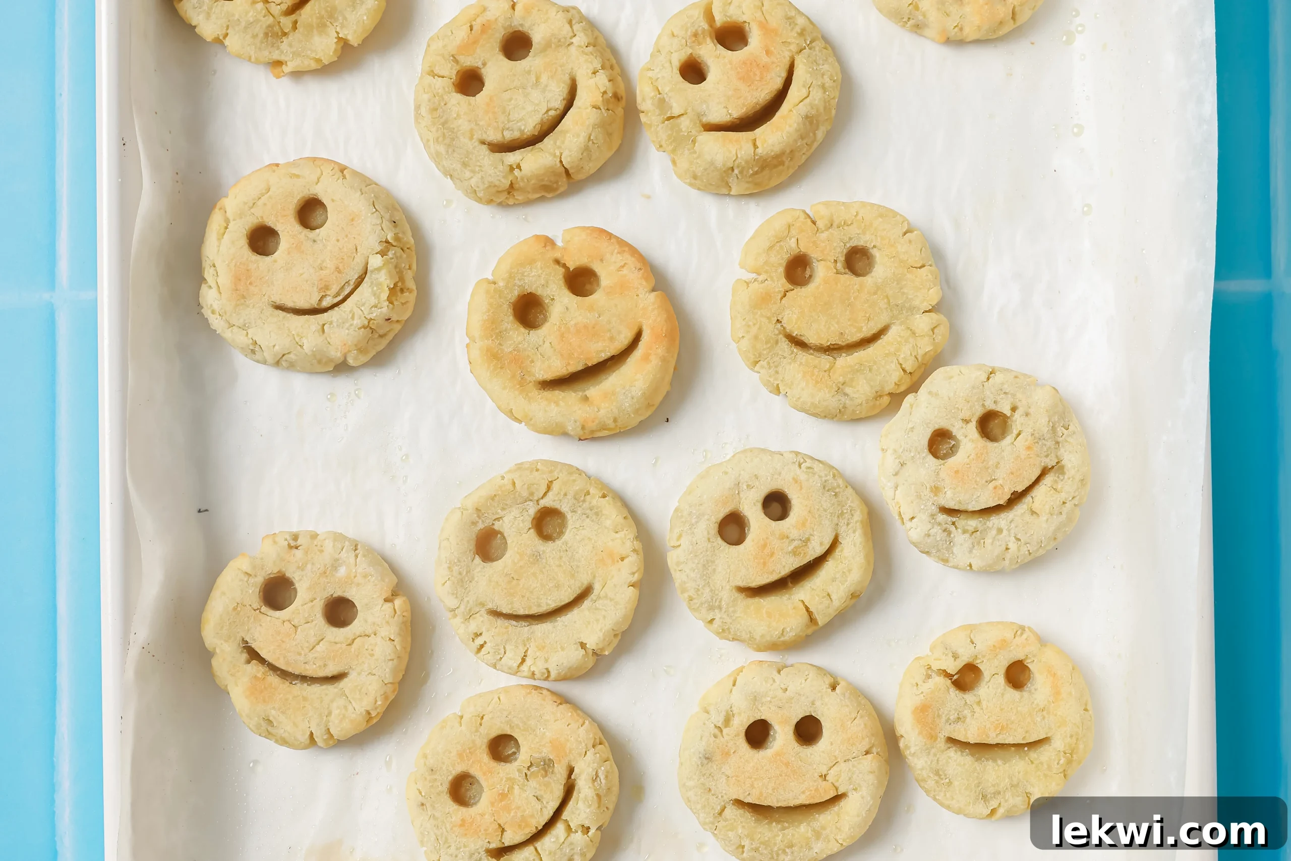 Baked sweet potato smiley fries golden brown and ready to eat on a baking sheet, showing their crispy texture and happy faces.