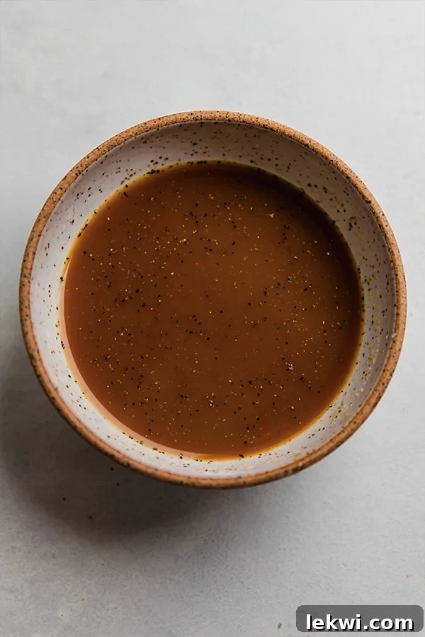 A close-up shot of a bowl containing freshly made orange chicken sauce, showcasing its rich color and smooth texture.