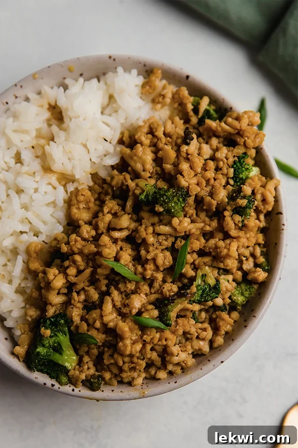 Ground orange chicken in a bowl with rice.