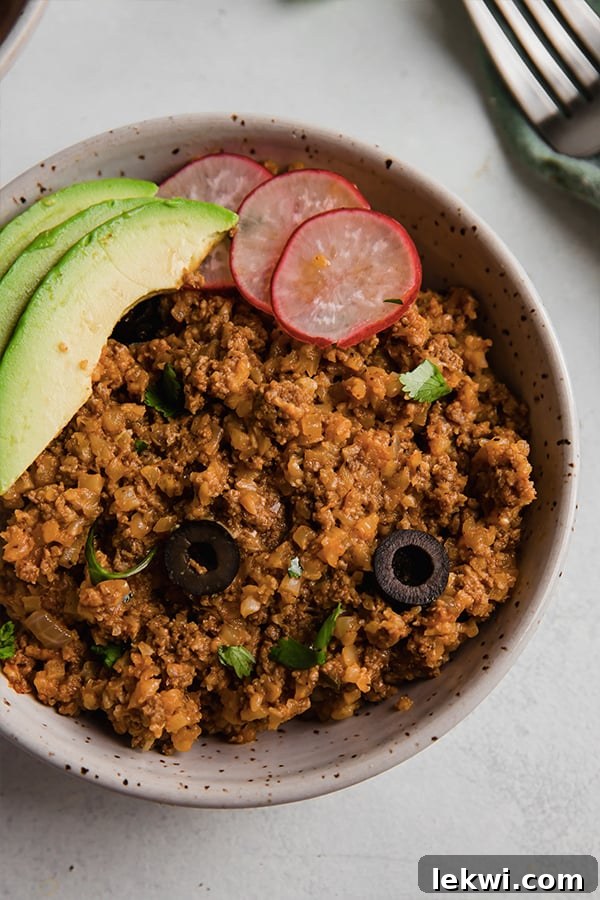 Ground beef and cauliflower rice enchilada in a bowl with avocado.