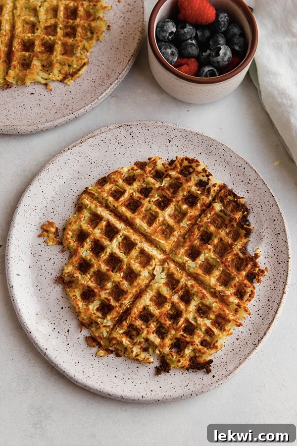 A perfectly cooked sweet potato hashbrown waffle on a plate, garnished and ready to eat.