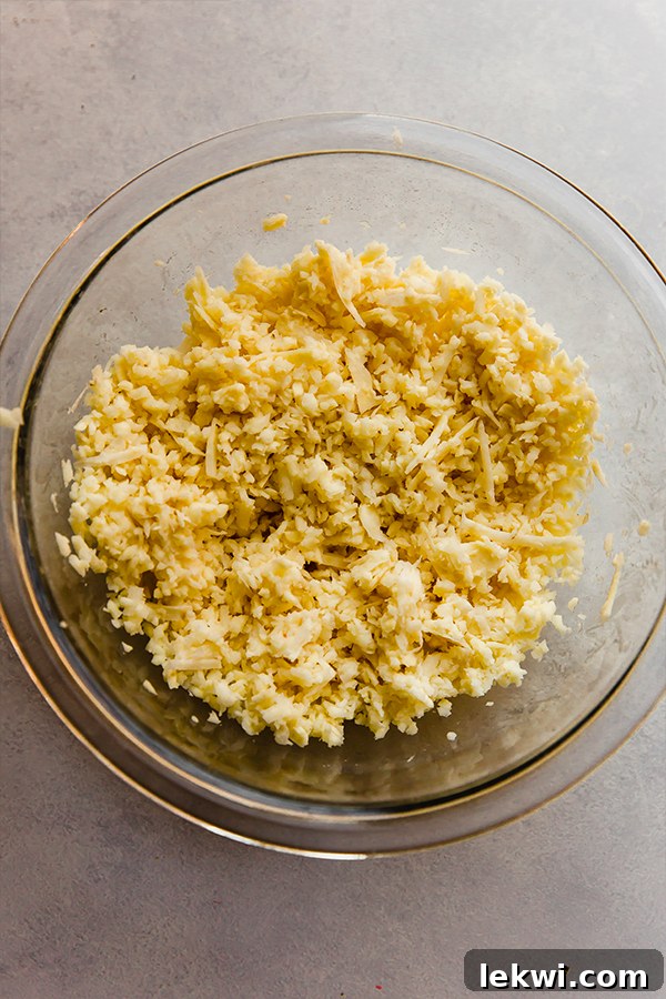 A bowl of finely shredded sweet potato mixed with other ingredients, ready for the waffle iron.