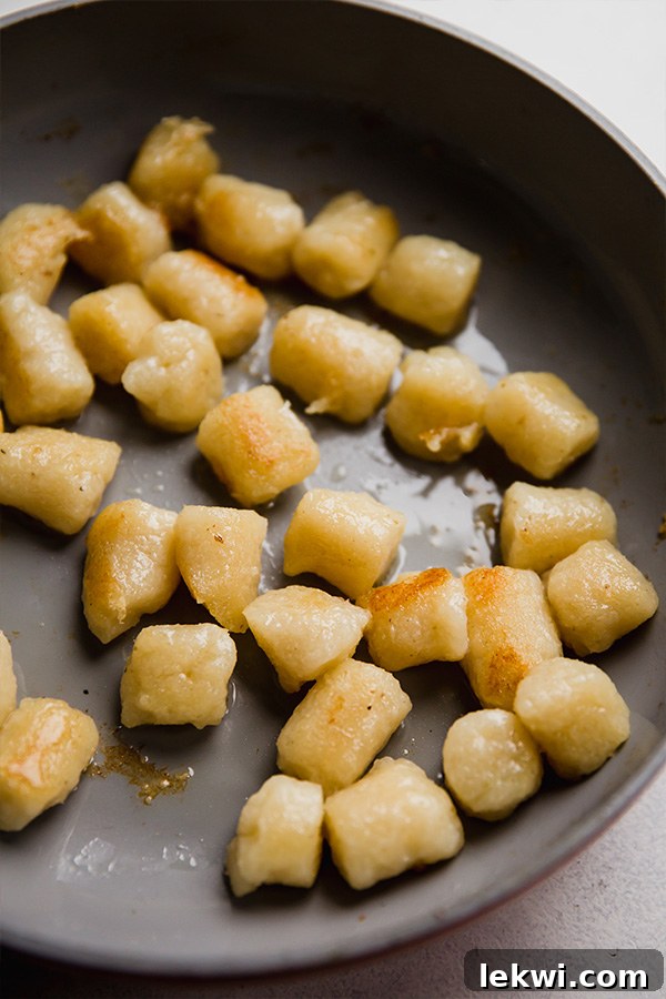 Close-up of cauliflower gnocchi browning in a skillet, creating a crispy exterior.
