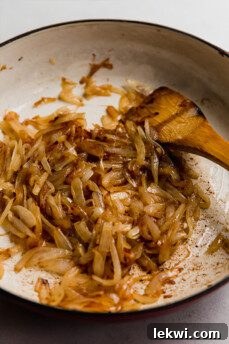 Wooden spatula in a pan with onion.