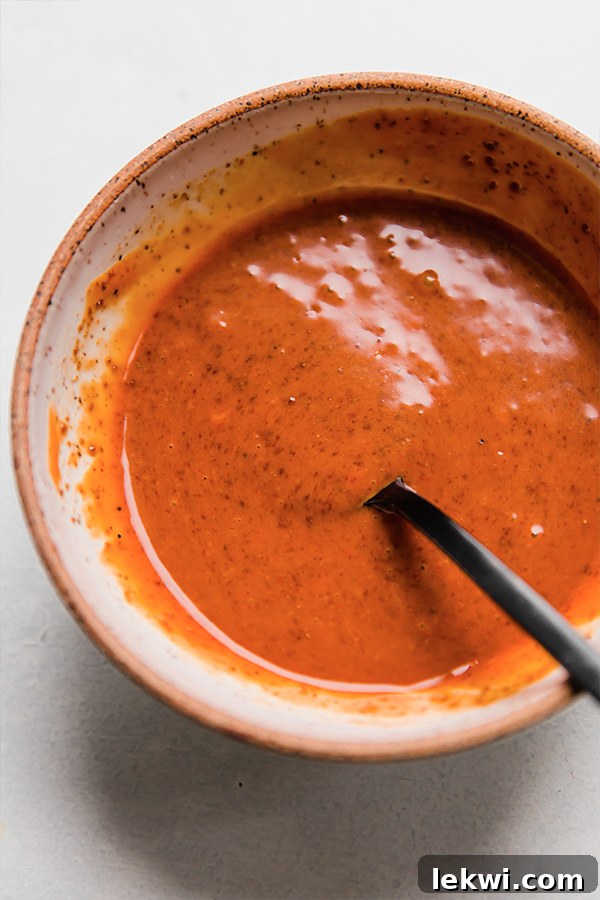 A close-up of a glass bowl containing the vibrant orange-red firecracker sauce, indicating it's freshly mixed and ready for use. The texture is smooth and inviting.