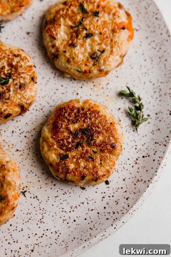 Perfectly cooked turkey breakfast sausage patties on a white plate, garnished with fresh herbs.