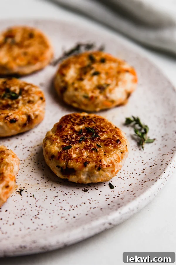 A beautifully presented plate with three turkey breakfast sausages, garnished with a sprig of fresh thyme.