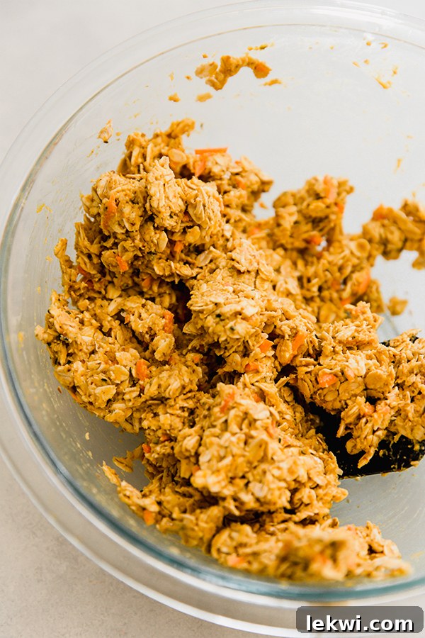 A close-up of a bowl filled with applesauce cookie dough, rich with oats, carrots, and sweet potato, showcasing its perfectly sticky yet firm texture.