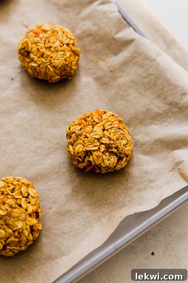 A batch of freshly baked applesauce carrot cookies cooling on a lined baking sheet, their wholesome appearance promising a healthy and delicious treat.