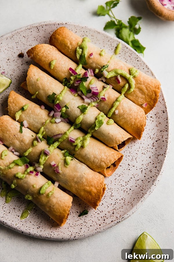 Sweet potato and beef breakfast taquitos drizzled with a vibrant green sauce, arranged neatly on a serving plate.