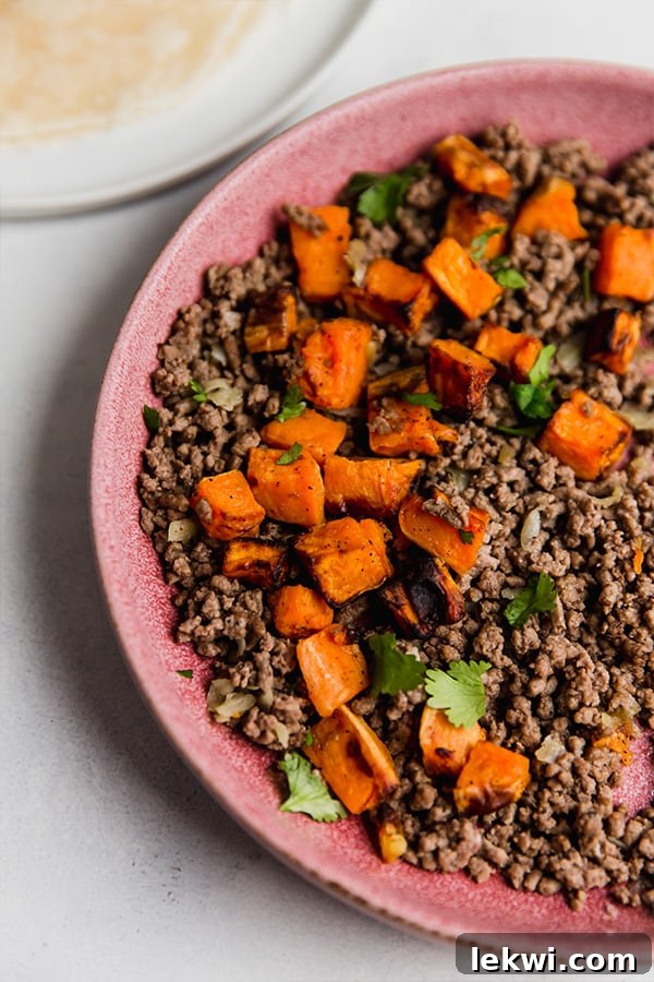 A vibrant bowl filled with the cooked sweet potato and seasoned ground beef mixture, ready for taquito assembly.