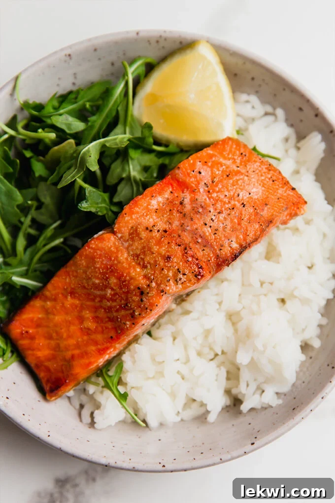 A bowl with air fryer salmon, arugula, and steamed rice. Delicious and healthy meal.
