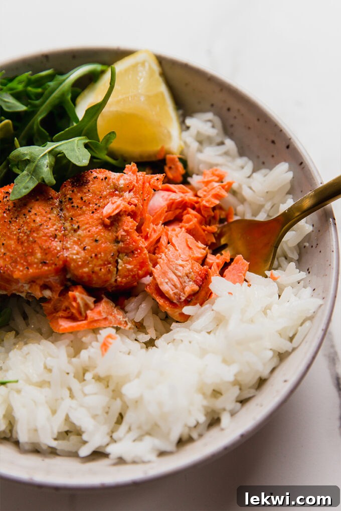 Fork flaking apart salmon, demonstrating perfect doneness.