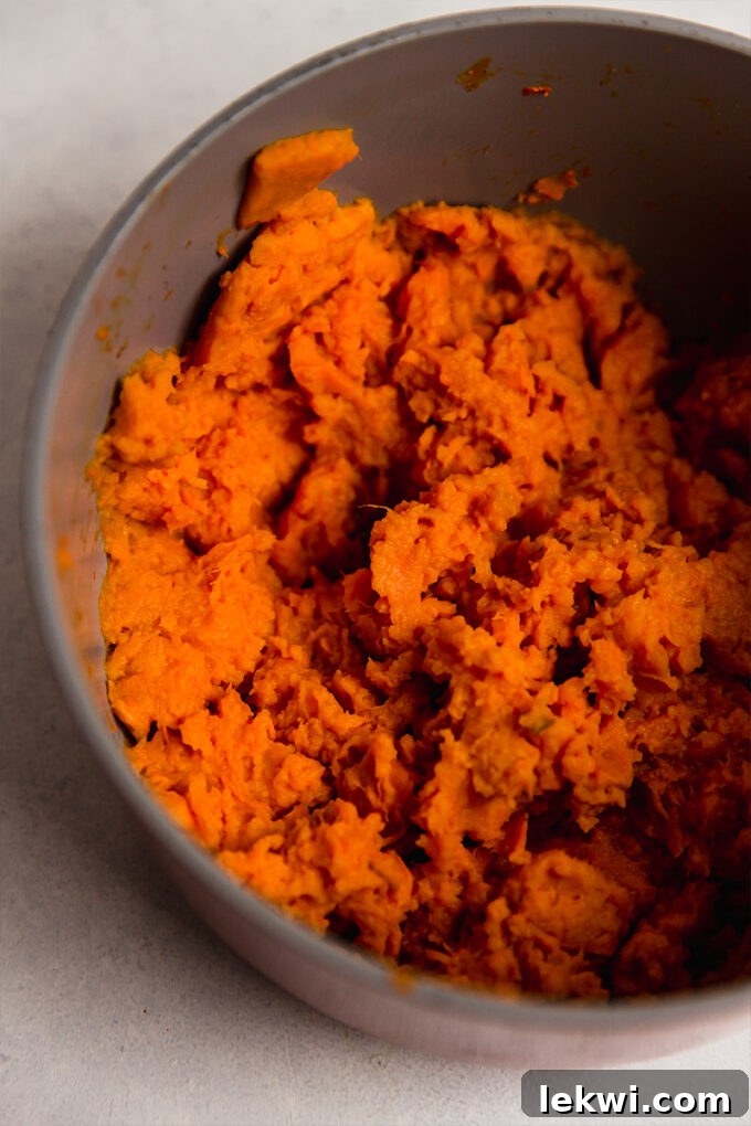 A bowl of freshly mashed sweet potatoes, smooth and creamy, ready for the pie topping.