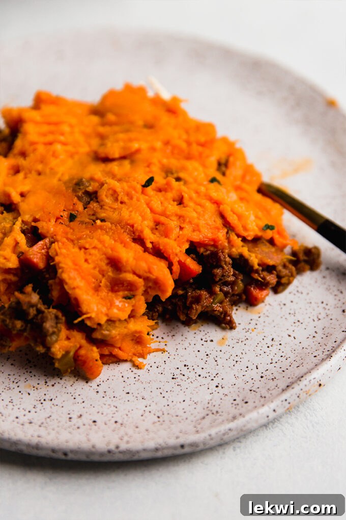 A single serving of sweet potato shepherd's pie on a white plate, garnished with fresh parsley.