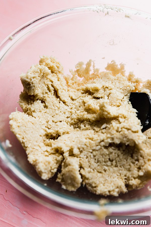 The combined macaroon dough mixture in a clear glass bowl, ready for scooping.