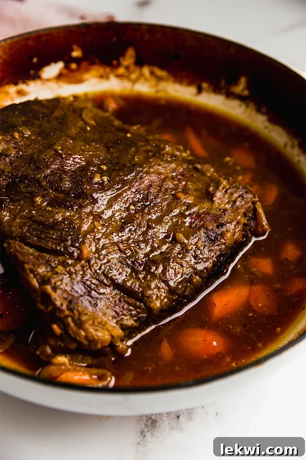 Brisket braising in a Dutch oven with vegetables and sauce.