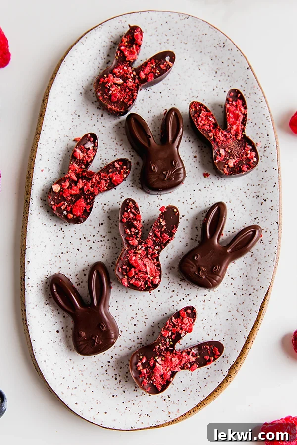 Exquisite dairy-free chocolate Easter bunnies adorned with vibrant freeze-dried strawberries, resting gracefully against a soft, blurred background, showcasing their perfect homemade charm for a healthy Easter treat.