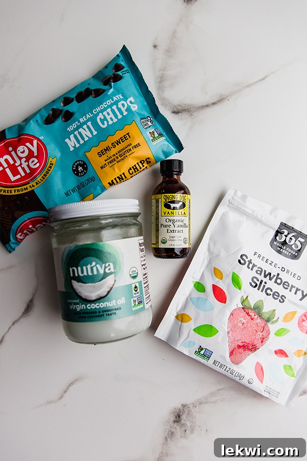 A thoughtful arrangement of all the core ingredients required to make delicious dairy-free chocolate Easter bunnies, including dairy-free chocolate chips, coconut oil, vanilla extract, and freeze-dried strawberries.