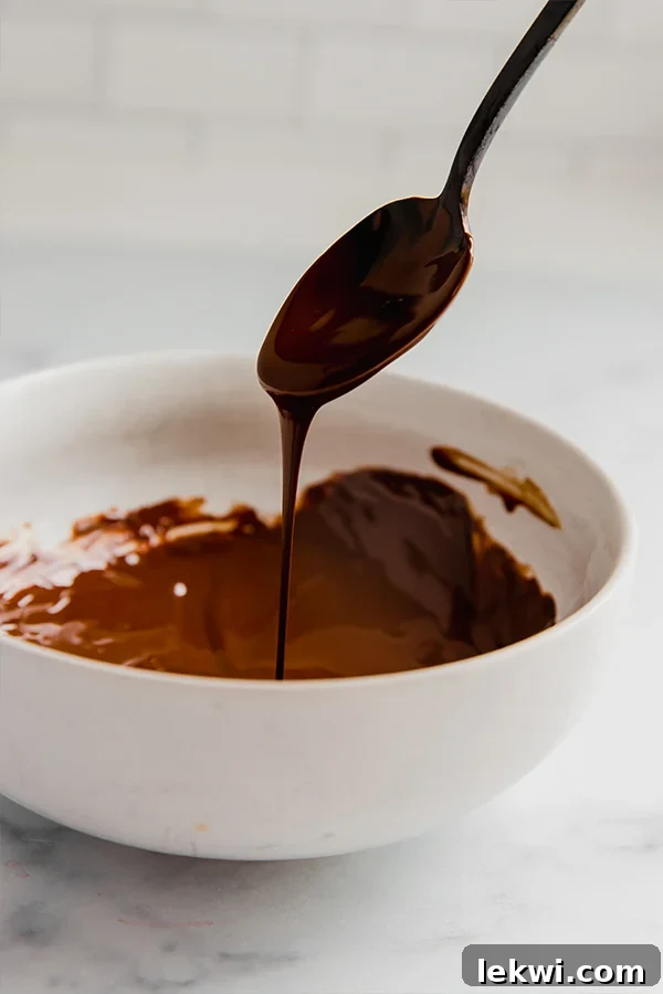 A bowl filled with perfectly melted dairy-free chocolate, glistening and smooth, ready to be poured into molds for making chocolate Easter bunnies.