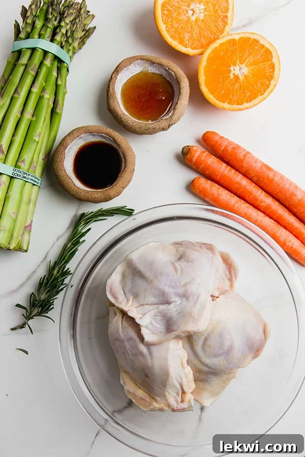 A collection of fresh ingredients neatly arranged, including vibrant oranges, a bunch of green asparagus, peeled carrots, a bowl of golden honey, a bottle of avocado oil, and aromatic rosemary sprigs, ready for cooking.