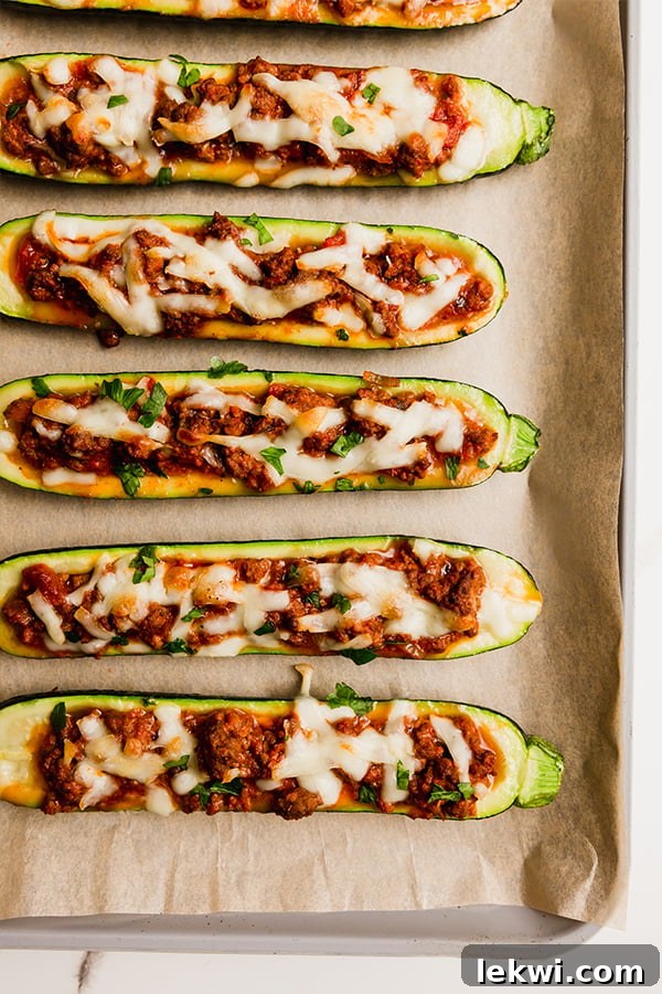 Several delicious Beef Stuffed Zucchini Boats beautifully arranged on a lined baking sheet, ready to be served as a healthy meal.