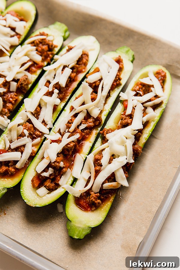 Richly stuffed beef zucchini boats, topped with a generous layer of cheese, arranged on a baking sheet and perfectly poised for the oven.