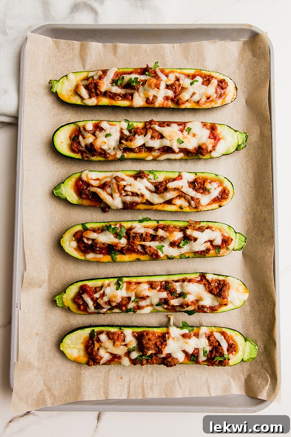 A vibrant, close-up shot of a freshly baked easy beef stuffed zucchini boat, golden and bubbly, served on a sheetpan with a fork, ready to be enjoyed.