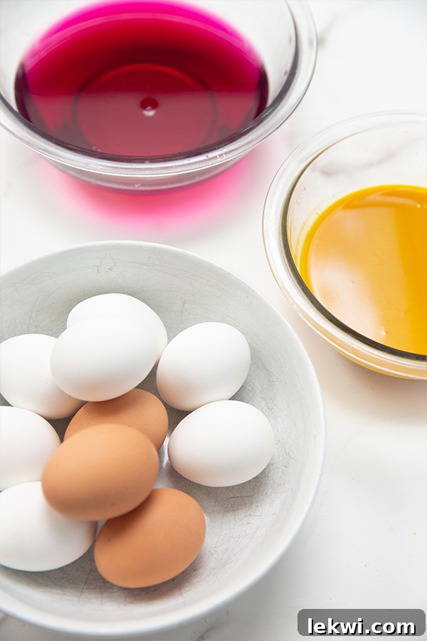 Two glass jars filled with homemade natural egg dyes—one with a deep blue red cabbage dye and the other with a vibrant yellow turmeric dye—alongside several plain hard-boiled eggs.