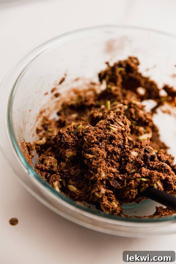 A bowl filled with raw chocolate zucchini muffin batter, ready for baking.