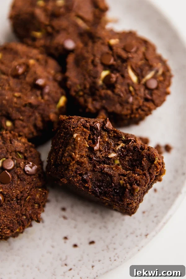 Rich chocolate zucchini muffins, one with a missing bite, ready to be enjoyed.