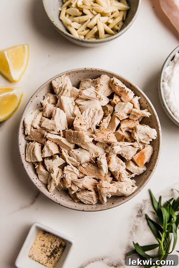 A bowl filled with succulent cooked chicken pieces, diced and ready to be mixed into the creamy and flavorful tarragon chicken salad.