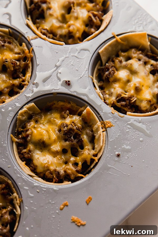 A tray filled with freshly baked mini taco cups, golden brown and ready to be removed from the oven.